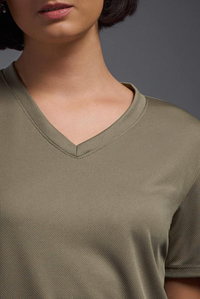 A female model with brown short hair on a gray background, wearing the Women's Oxymesh™ V-neck Tech Tee in the color tan-499 from a closeup collar front view. This shirt is made in the USA and is quick-drying and moisture-wicking. #color_tan-499