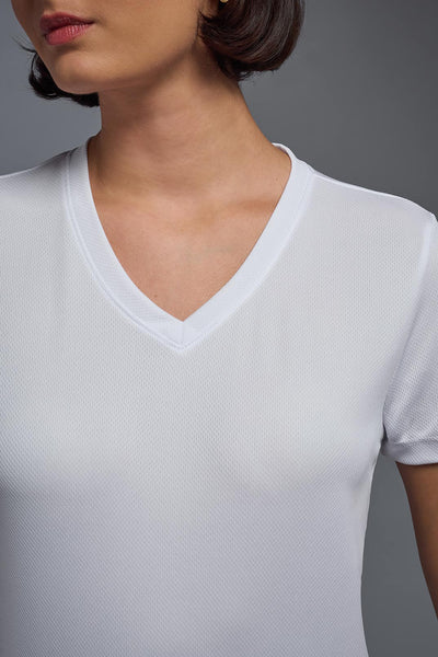A female model with brown short hair on a gray background, wearing the Women's Oxymesh™ V-neck Tech Tee in the color white from a closeup collar front view. This shirt is made in the USA and is quick-drying and moisture-wicking. #color_white