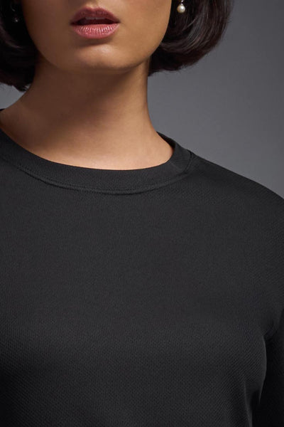 A female model with short brown hair on a gray background, wearing the Women's Oxymesh™ Long Sleeve Tech Tee in the color black from a closeup collar view. This shirt is made in the USA and is quick-drying and moisture-wicking. #color_black