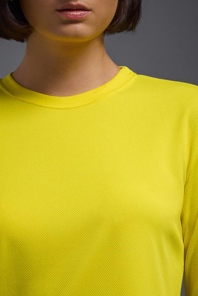 A female model with short brown hair on a gray background, wearing the Women's Oxymesh™ Long Sleeve Tech Tee in the color bright yellow from a closeup collar front view. This shirt is made in the USA and is quick-drying and moisture-wicking. #color_bright-yellow