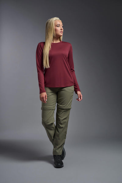 A blonde, female model with long straight hair on a gray background, wearing the Women's Oxymesh™ Long Sleeve Tech Tee in the color cardinal from a full body front view. This shirt is made in the USA and is quick-drying and moisture-wicking. #color_cardinal