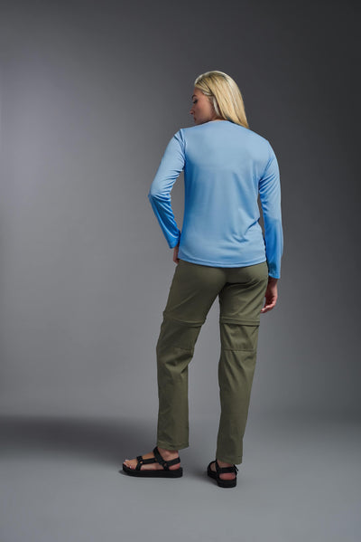 A blonde, female model with long straight hair on a gray background, wearing the Women's Oxymesh™ Long Sleeve Tech Tee in the color carolina blue from a full body back view. This shirt is made in the USA and is quick-drying and moisture-wicking. #color_carolina-blue