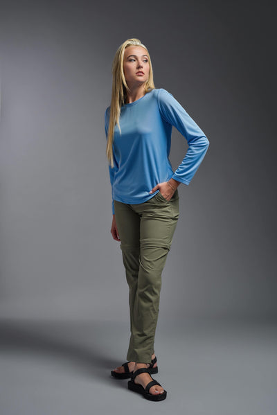 A blonde, female model with long straight hair on a gray background, wearing the Women's Oxymesh™ Long Sleeve Tech Tee in the color carolina blue from a full body side view. This shirt is made in the USA and is quick-drying and moisture-wicking. #color_carolina-blue
