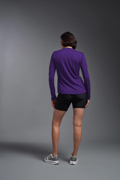 A female model with short brown hair on a gray background, wearing the Women's Oxymesh™ Long Sleeve Tech Tee in the color dark purple from a full body back view. This shirt is made in the USA and is quick-drying and moisture-wicking. #color_dark-purple