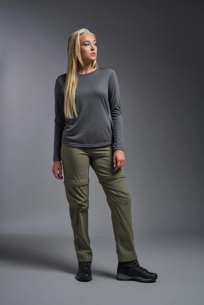 A blonde, female model with long straight hair on a gray background, wearing the Women's Oxymesh™ Long Sleeve Tech Tee in the color graphite gray from a full body front view. This shirt is made in the USA and is quick-drying and moisture-wicking. #color_graphite-gray