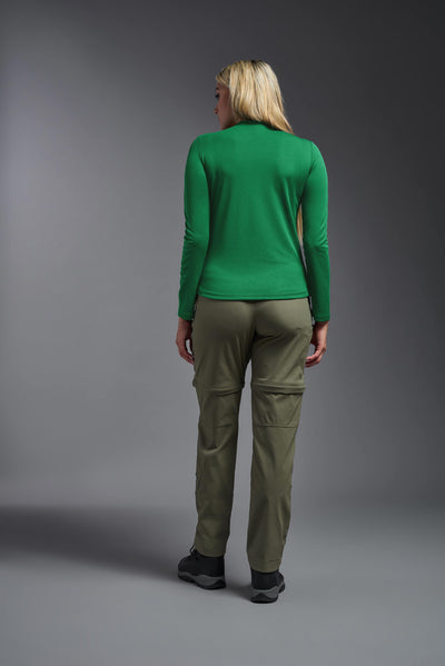 A blonde female model with long straight hair on a gray background, wearing the Women's Oxymesh™ Long Sleeve Tech Tee in the color kelly green from a full body back view. This shirt is made in the USA and is quick-drying and moisture-wicking. #color_kelly-green