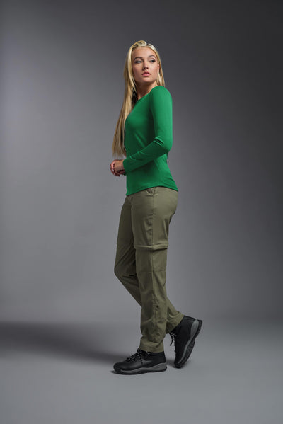 A blonde female model with long straight hair on a gray background, wearing the Women's Oxymesh™ Long Sleeve Tech Tee in the color kelly green from a full body side view. This shirt is made in the USA and is quick-drying and moisture-wicking. #color_kelly-green