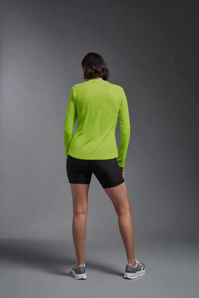 A female model with short brown hair on a gray background, wearing the Women's Oxymesh™ Long Sleeve Tech Tee in the color key lime from a full body back view. This shirt is made in the USA and is quick-drying and moisture-wicking. #color_key-lime