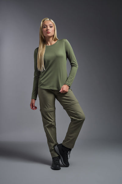 A blonde female model with long straight hair on a gray background, wearing the Women's Oxymesh™ Long Sleeve Tech Tee in the color military green from a full body front view. This shirt is made in the USA and is quick-drying and moisture-wicking. #color_military-green