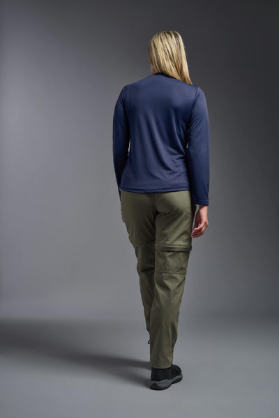A blonde, female model with long straight hair on a gray background, wearing the Women's Oxymesh™ Long Sleeve Tech Tee in the color navy blue from a full body back view. This shirt is made in the USA and is quick-drying and moisture-wicking. #color_navy-blue