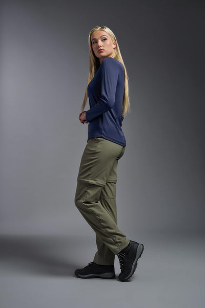 A blonde, female model with long straight hair on a gray background, wearing the Women's Oxymesh™ Long Sleeve Tech Tee in the color navy blue from a full body side view. This shirt is made in the USA and is quick-drying and moisture-wicking. #color_navy-blue