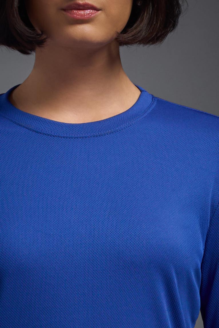A female model with short brown hair on a gray background, wearing the Women's Oxymesh™ Long Sleeve Tech Tee in the color royal blue from a closeup collar view. This shirt is made in the USA and is quick-drying and moisture-wicking. #color_royal-blue