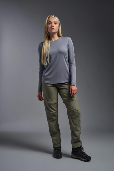 A blonde, female model with long straight hair on a gray background, wearing the Women's Oxymesh™ Long Sleeve Tech Tee in the color steel gray from a full body front view. This shirt is made in the USA and is quick-drying and moisture-wicking. #color_steel-gray