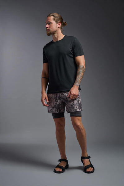 A blonde male model with a beard on a gray background, wearing the Men's Oxymesh™ Crewneck Tech Tee in the color black from a full body front view. This shirt is made in the USA and is quick-drying and moisture-wicking. #color_black
