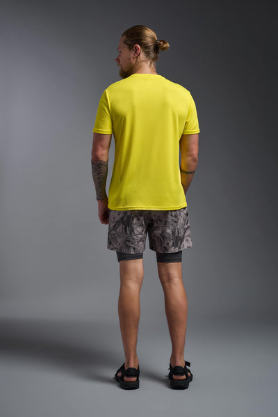 A blonde male model with a beard on a gray background, wearing the Men's Oxymesh™ Crewneck Tech Tee in the color bright yellow from a full body back view. This shirt is made in the USA and is quick-drying and moisture-wicking. #color_bright-yellow