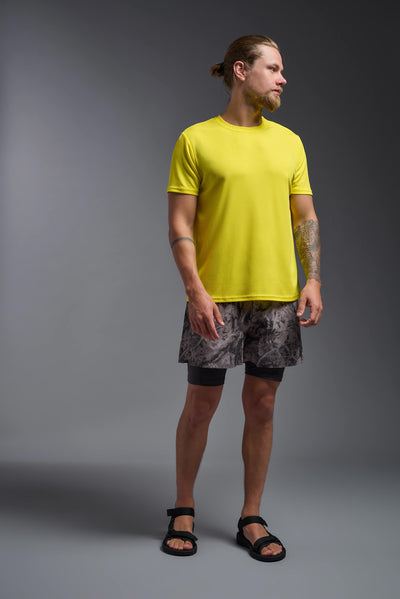 A blonde male model with a beard on a gray background, wearing the Men's Oxymesh™ Crewneck Tech Tee in the color bright yellow from a full body front view. This shirt is made in the USA and is quick-drying and moisture-wicking. #color_bright-yellow