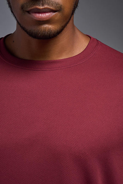 An African American male model with a beard on a gray background, wearing the Men's Oxymesh™ Crewneck Tech Tee in the color cardinal from a closeup collar front view. This shirt is made in the USA and is quick-drying and moisture-wicking. #color_cardinal