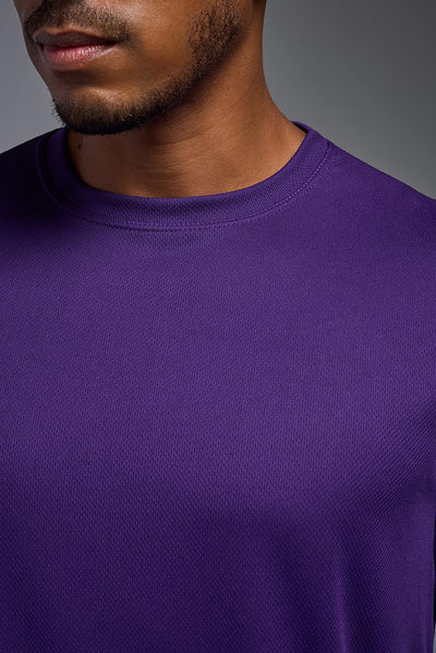 An African American male model with a beard on a gray background, wearing the Men's Oxymesh™ Crewneck Tech Tee in the color dark purple from a closeup collar front view. This shirt is made in the USA and is quick-drying and moisture-wicking. #color_dark-purple