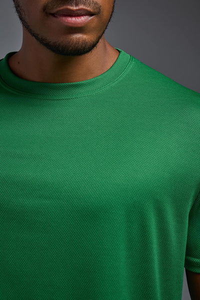 An African American male model with a beard on a gray background, wearing the Men's Oxymesh™ Crewneck Tech Tee in the color kelly green from a closeup collar front view. This shirt is made in the USA and is quick-drying and moisture-wicking. #color_kelly-green