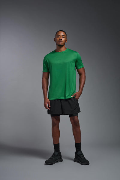 An African American male model with a beard on a gray background, wearing the Men's Oxymesh™ Crewneck Tech Tee in the color kelly green from a full body front view. This shirt is made in the USA and is quick-drying and moisture-wicking. #color_kelly-green