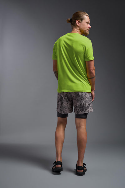 A blonde male model with a beard on a gray background, wearing the Men's Oxymesh™ Crewneck Tech Tee in the color key lime from a full body back view. This shirt is made in the USA and is quick-drying and moisture-wicking. #color_key-lime