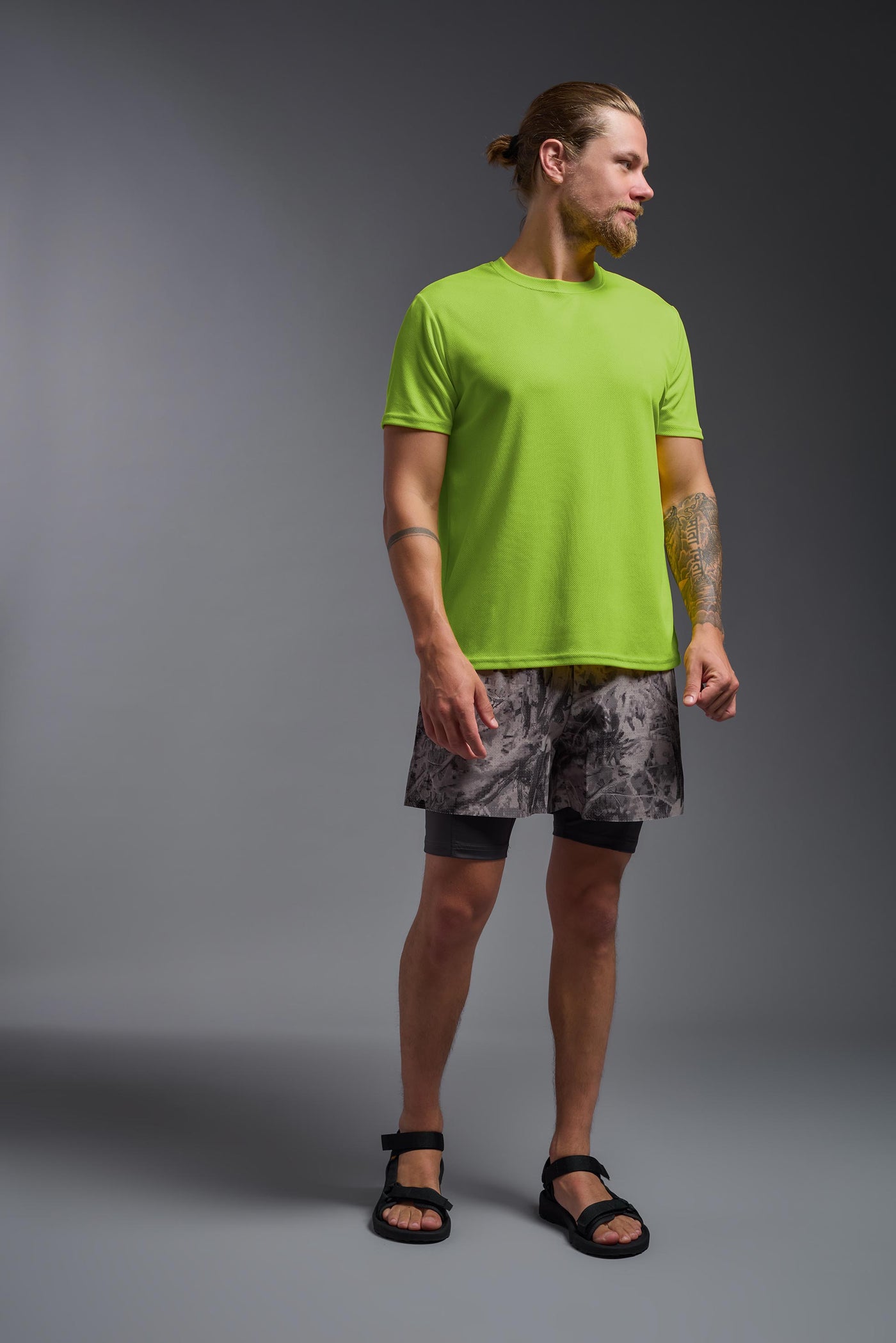 A blonde male model with a beard on a gray background, wearing the Men's Oxymesh™ Crewneck Tech Tee in the color key lime from a full body front view. This shirt is made in the USA and is quick-drying and moisture-wicking. #color_key-lime