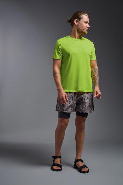 A blonde male model with a beard on a gray background, wearing the Men's Oxymesh™ Crewneck Tech Tee in the color key lime from a full body front view. This shirt is made in the USA and is quick-drying and moisture-wicking. #color_key-lime