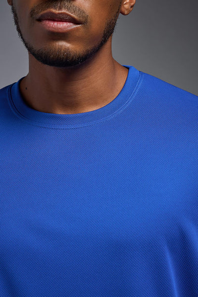 An African American male model with a beard on a gray background, wearing the Men's Oxymesh™ Crewneck Tech Tee in the color royal blue from a closeup collar front view. This shirt is made in the USA and is quick-drying and moisture-wicking. #color_royal-blue