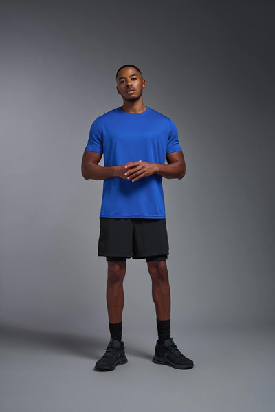 An African American male model with a beard on a gray background, wearing the Men's Oxymesh™ Crewneck Tech Tee in the color royal blue from a full body front view. This shirt is made in the USA and is quick-drying and moisture-wicking. #color_royal-blue