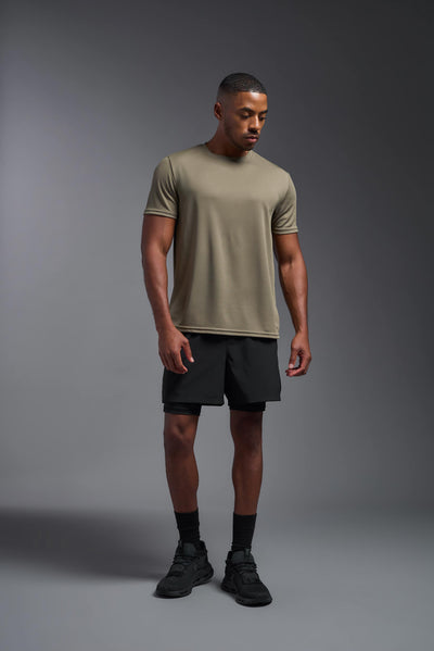 An African American male model with a beard on a gray background, wearing the Men's Oxymesh™ Crewneck Tech Tee in the color tan-499 from a full body front view. This shirt is made in the USA and is quick-drying and moisture-wicking. #color_tan-499