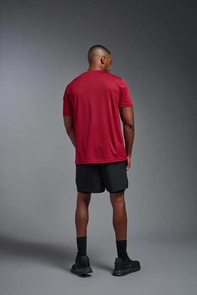 An African American male model with a beard on a gray background, wearing the Men's Oxymesh™ Crewneck Tech Tee in the color true red from a full body back view. This shirt is made in the USA and is quick-drying and moisture-wicking. #color_true-red