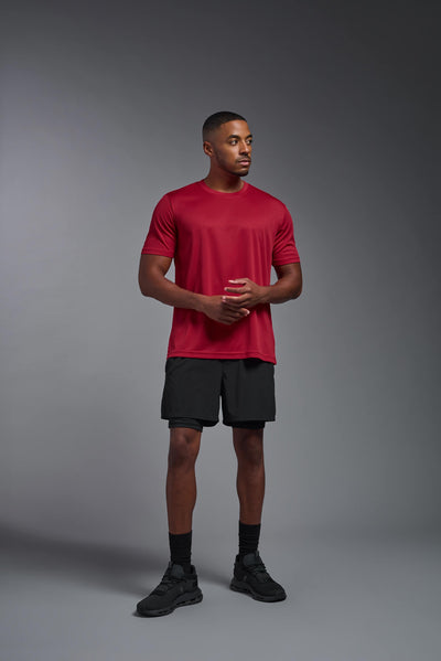 An African American male model with a beard on a gray background, wearing the Men's Oxymesh™ Crewneck Tech Tee in the color true red from a full body front view. This shirt is made in the USA and is quick-drying and moisture-wicking. #color_true-red