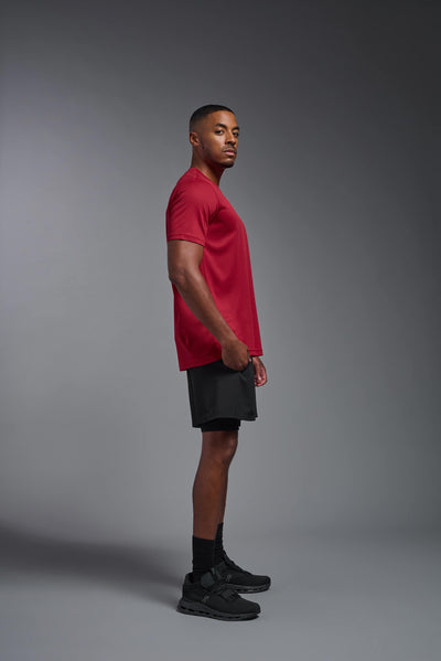An African American male model with a beard on a gray background, wearing the Men's Oxymesh™ Crewneck Tech Tee in the color true red from a full body side view. This shirt is made in the USA and is quick-drying and moisture-wicking. #color_true-red