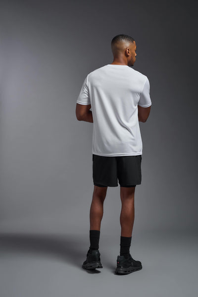 An African American male model with a beard on a gray background, wearing the Men's Oxymesh™ Crewneck Tech Tee in the color white from a full body back view. This shirt is made in the USA and is quick-drying and moisture-wicking. #color_white
