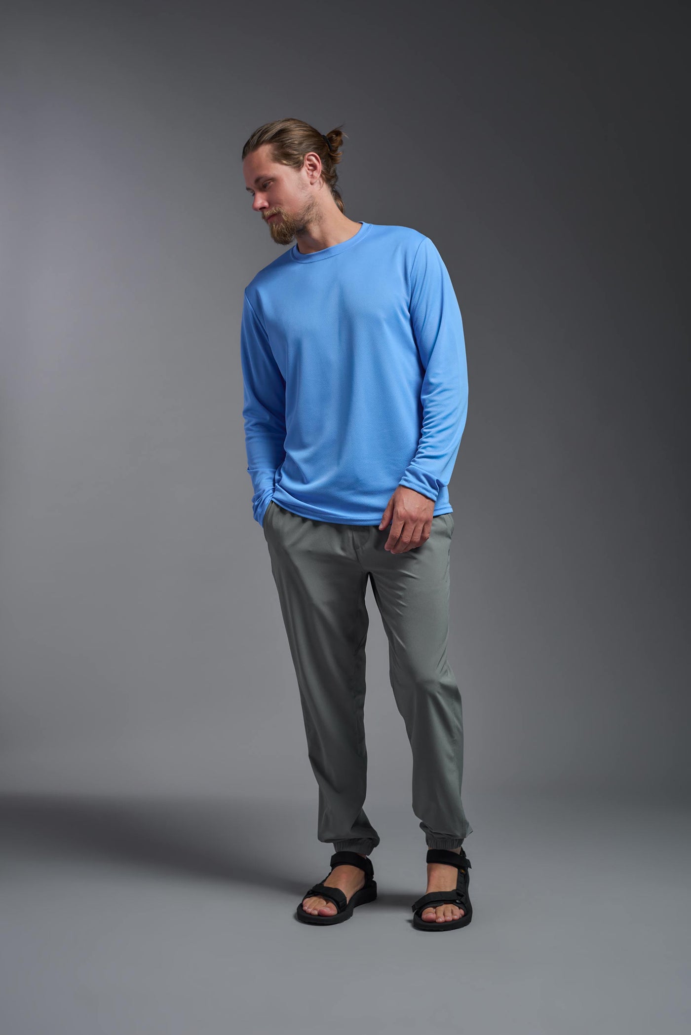 A blonde Caucasian model with a beard wearing the men's Oxymesh Long Sleeve Tech Tee in the color carolina blue on a gray background, made out of 100% polyester, showing the relaxed fit from a full body front view. This shirt is breathable, quick-drying, moisture-wicking, and made in the USA. #color_carolina-blue