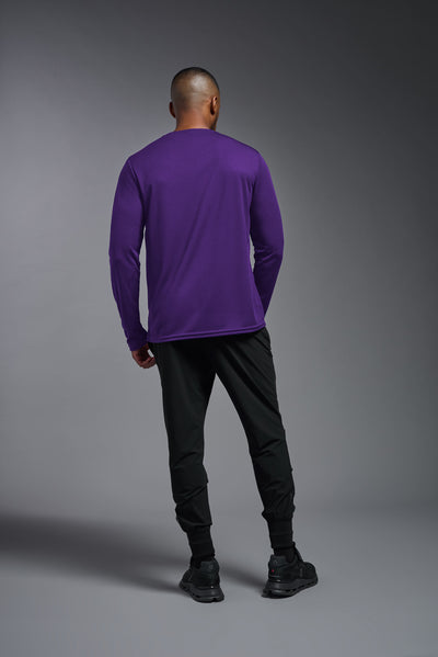 An African American male model with a beard wearing the men's Oxymesh Long Sleeve Tech Tee in the color dark purple, made out of 100% polyester, showing the relaxed fit from a full body back view. This shirt is breathable, quick-drying, moisture-wicking, and made in the USA. #color_dark-purple