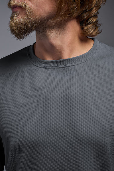 A blonde American male model with a beard wearing the men's Oxymesh Long Sleeve Tech Tee in the color graphite gray, made out of 100% polyester, showing the relaxed fit from a closeup collar front view. This shirt is breathable, quick-drying, moisture-wicking, and made in the USA. #color_graphite-gray