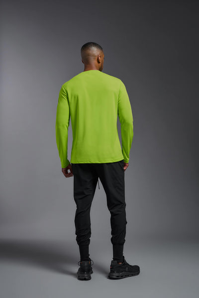 An African American male model with a beard wearing the men's Oxymesh Long Sleeve Tech Tee in the color key lime on a gray background, made out of 100% polyester, showing the relaxed fit from a full body back view. This shirt is breathable, quick-drying, moisture-wicking, and made in the USA. #color_key-lime