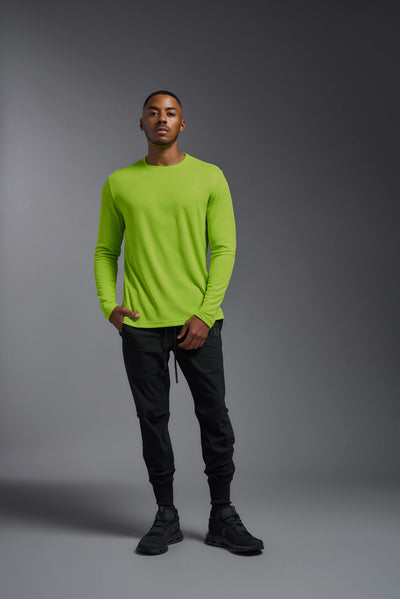 An African American male model with a beard wearing the men's Oxymesh Long Sleeve Tech Tee in the color key lime on a gray background, made out of 100% polyester, showing the relaxed fit from a full body front view. This shirt is breathable, quick-drying, moisture-wicking, and made in the USA. #color_key-lime