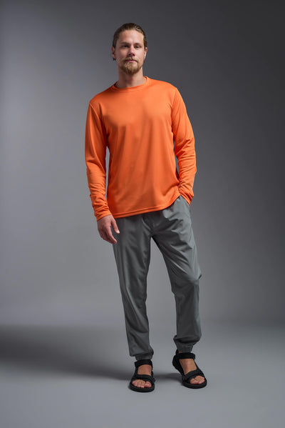 A blonde Caucasian model with a beard wearing the men's Oxymesh Long Sleeve Tech Tee in the color orange on a gray background, made out of 100% polyester, showing the relaxed fit from a full body front view. This shirt is breathable, quick-drying, moisture-wicking, and made in the USA. #color_orange