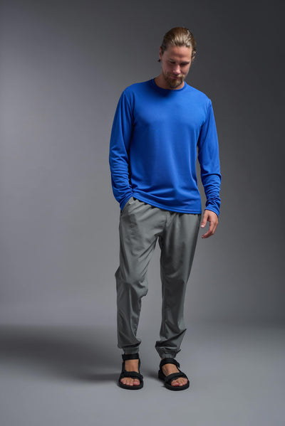 A blonde male model with a beard wearing the men's Oxymesh Long Sleeve Tech Tee in the color royal blue on a gray background, made out of 100% polyester, showing the relaxed fit from a full body front view. This shirt is breathable, quick-drying, moisture-wicking, and made in the USA. #color_royal-blue