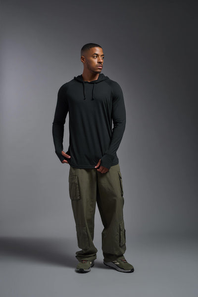 An African American, male model with a beard wearing the men's Siro Curvy Hoodie Shirt in the color black, made out of 100% polyester, showing the relaxed fit from a front view. This shirt features a soft cotton feel, quick-dries, wicks moisture and is made in the USA. #color_black