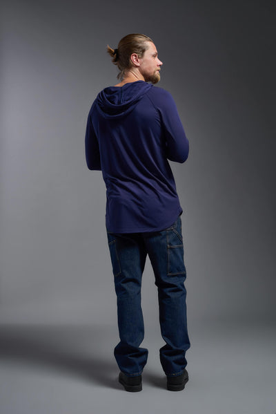 A blonde male model with a beard wearing the men's Siro Curvy Hoodie Shirt in the color navy, made out of 100% polyester, showing the relaxed fit from a back view. This hoodie shirt features a soft cotton feel, quick-dries, wicks moisture and is made in the USA. #color_navy