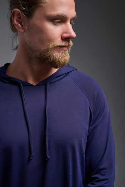 A blonde male model with a beard wearing the men's Siro Curvy Hoodie Shirt in the color navy, made out of 100% polyester, showing the relaxed fit from a front collar closeup view. This hoodie shirt features a soft cotton feel, quick-dries, wicks moisture and is made in the USA. #color_navy