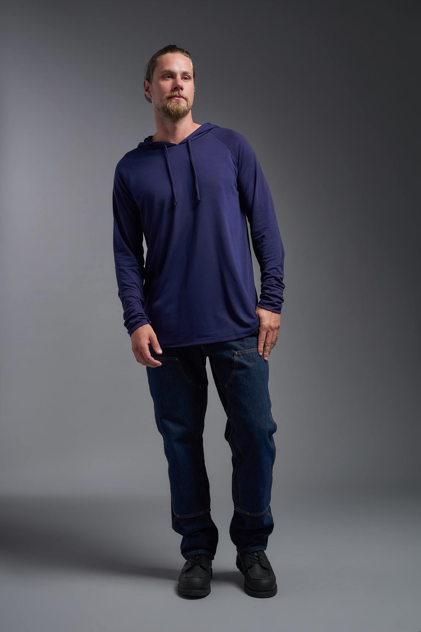 A blonde male model with a beard wearing the men's Siro Curvy Hoodie Shirt in the color navy, made out of 100% polyester, showing the relaxed fit from a front view. This hoodie shirt features a soft cotton feel, quick-dries, wicks moisture and is made in the USA. #color_navy