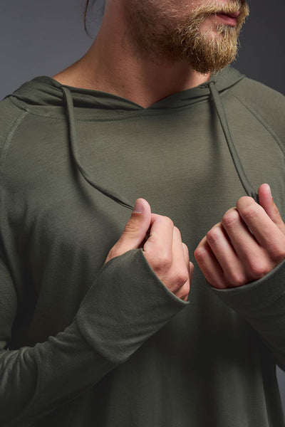 A blonde male model with a beard wearing the men's Siro Curvy Hoodie Shirt in the color olive, made out of 100% polyester, showing the relaxed fit from a closeup collar view. This hoodie shirt features a soft cotton feel, quick-dries, wicks moisture and is made in the USA. #color_olive