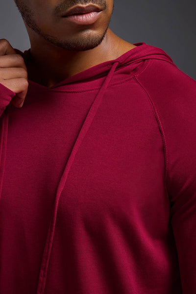 An African American, male model with a beard wearing the men's Siro Curvy Hoodie Shirt in the color scarlet, made out of 100% polyester, showing the relaxed fit from a front collar detail view. This shirt features a soft cotton feel, quick-dries, wicks moisture and is made in the USA. #color_scarlet