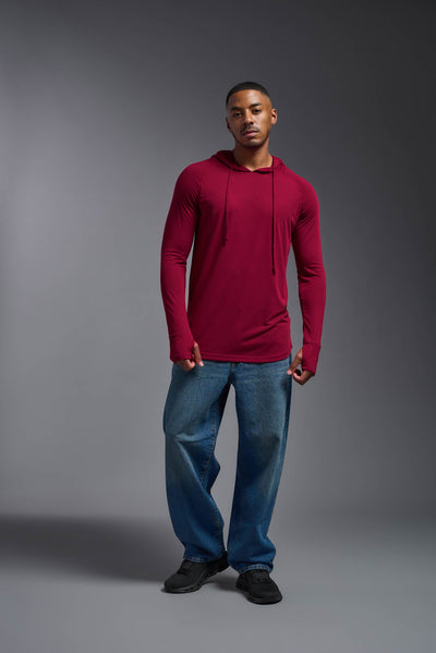 An African American, male model with a beard wearing the men's Siro Curvy Hoodie Shirt in the color scarlet, made out of 100% polyester, showing the relaxed fit from a front view. This shirt features a soft cotton feel, quick-dries, wicks moisture and is made in the USA. #color_scarlet