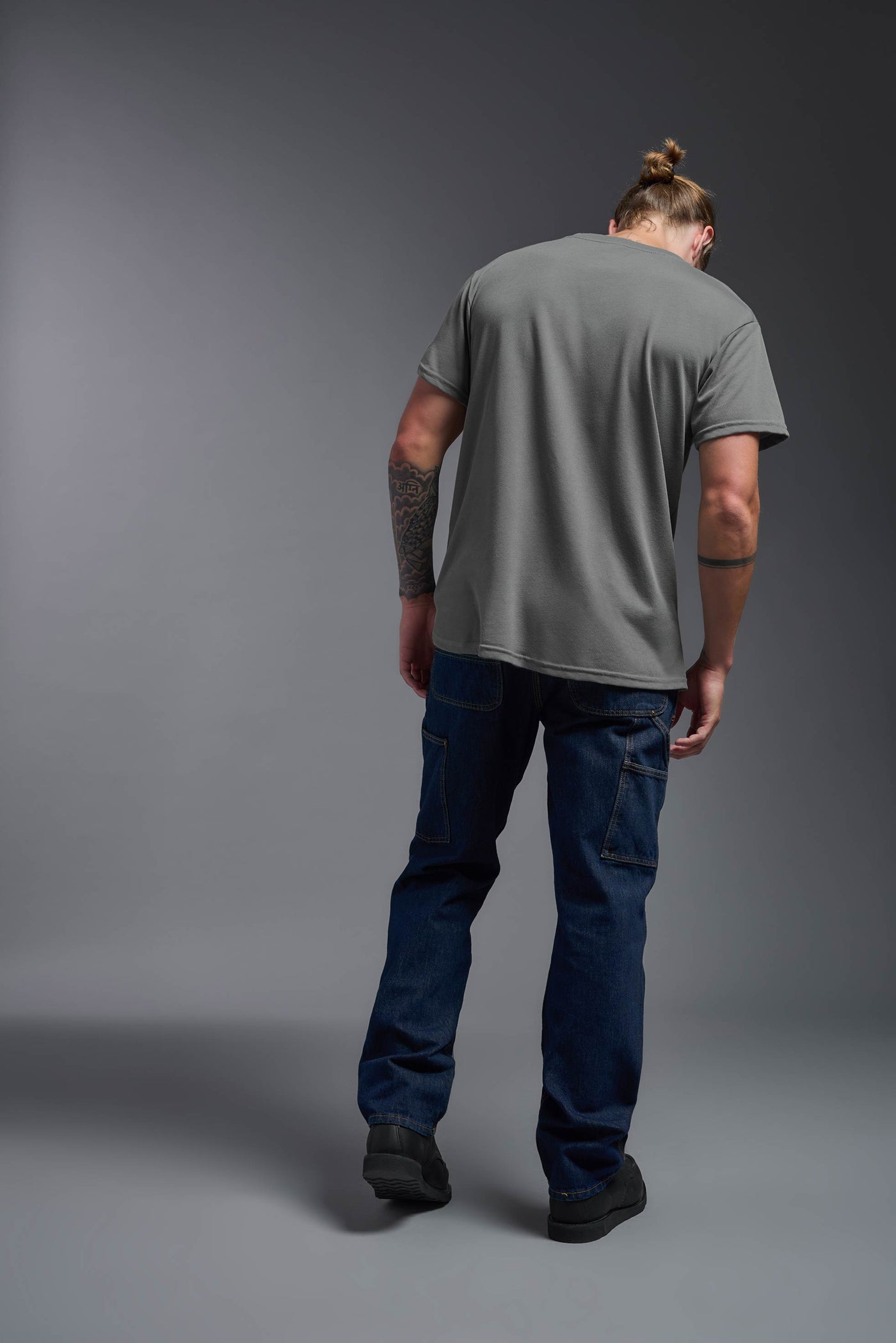 A male caucasian model with a beard wearing the men's DuroSoft Outdoor Tee in the color army gray on a gray background, made out of 100% filament polyester that feels like soft cotton, showing the modern fit from a back view. This shirt is anti-snagging, quick-drying and moisture-wicking and is made in the USA. #color_army-gray