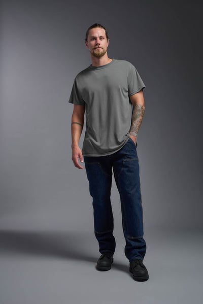 A male caucasian model with a beard wearing the men's DuroSoft Outdoor Tee in the color army gray on a gray background, made out of 100% filament polyester that feels like soft cotton, showing the modern fit from a back view. This shirt is anti-snagging, quick-drying and moisture-wicking and is made in the USA. #color_army-gray